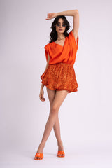 Neon orange draped top with padded shoulders and 'V' neckline