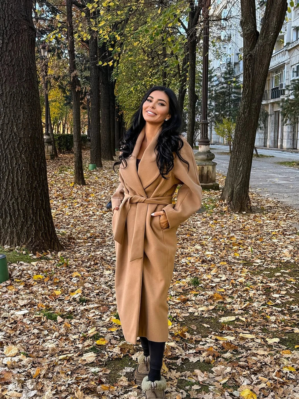 Palton camel BLUZAT cu cordon, purtat cu pantaloni negri pe o alee acoperită cu frunze